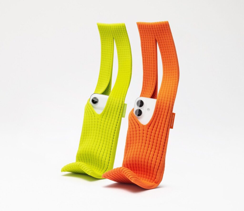 Two knitted iPhone Pocket accessories in neon green and orange, showing Apple's minimalist design and unique color choices that elevate a simple phone holder into a premium product.